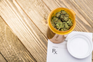 Stock image of medical marijuana buds in a prescription bottle sitting on top of a prescription pad.